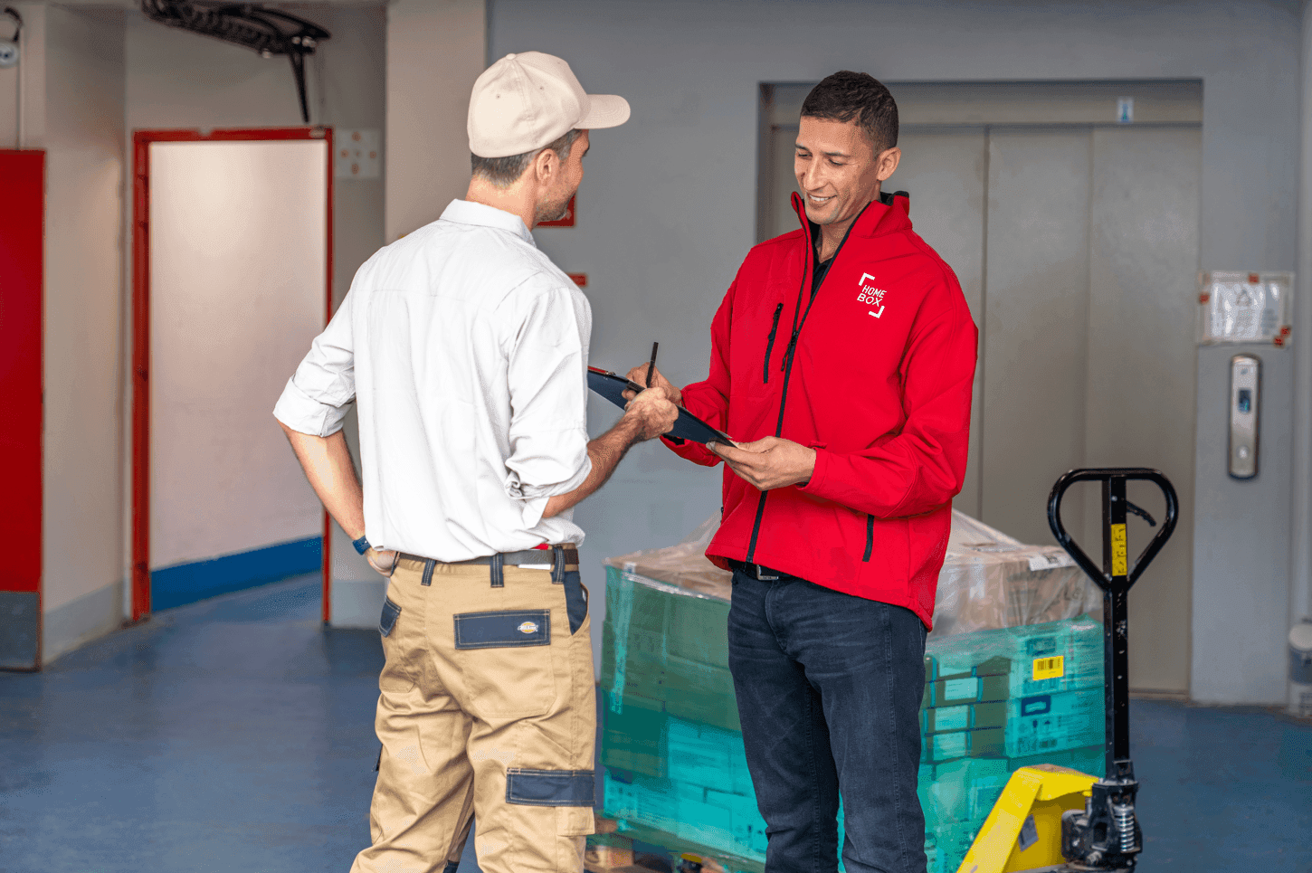 HOMEBOX employee in red jacket assisting a business client with pallet of goods