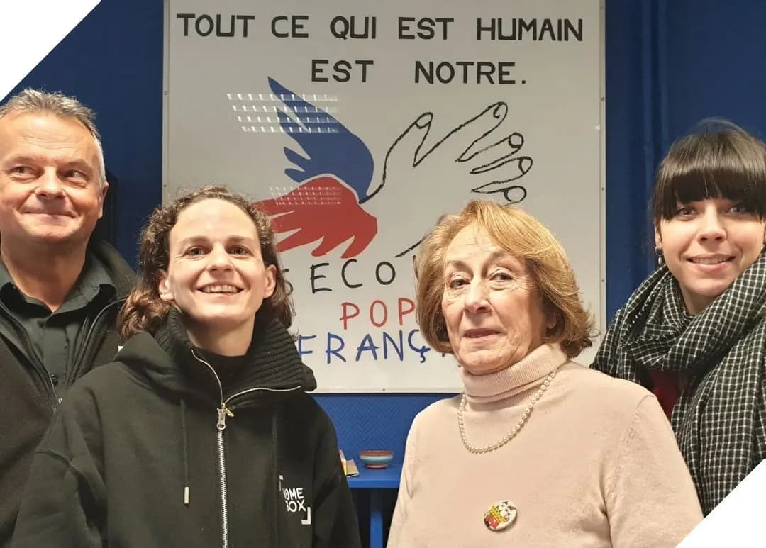 Équipe HOMEBOX posant devant l'affiche du Secours Populaire Français