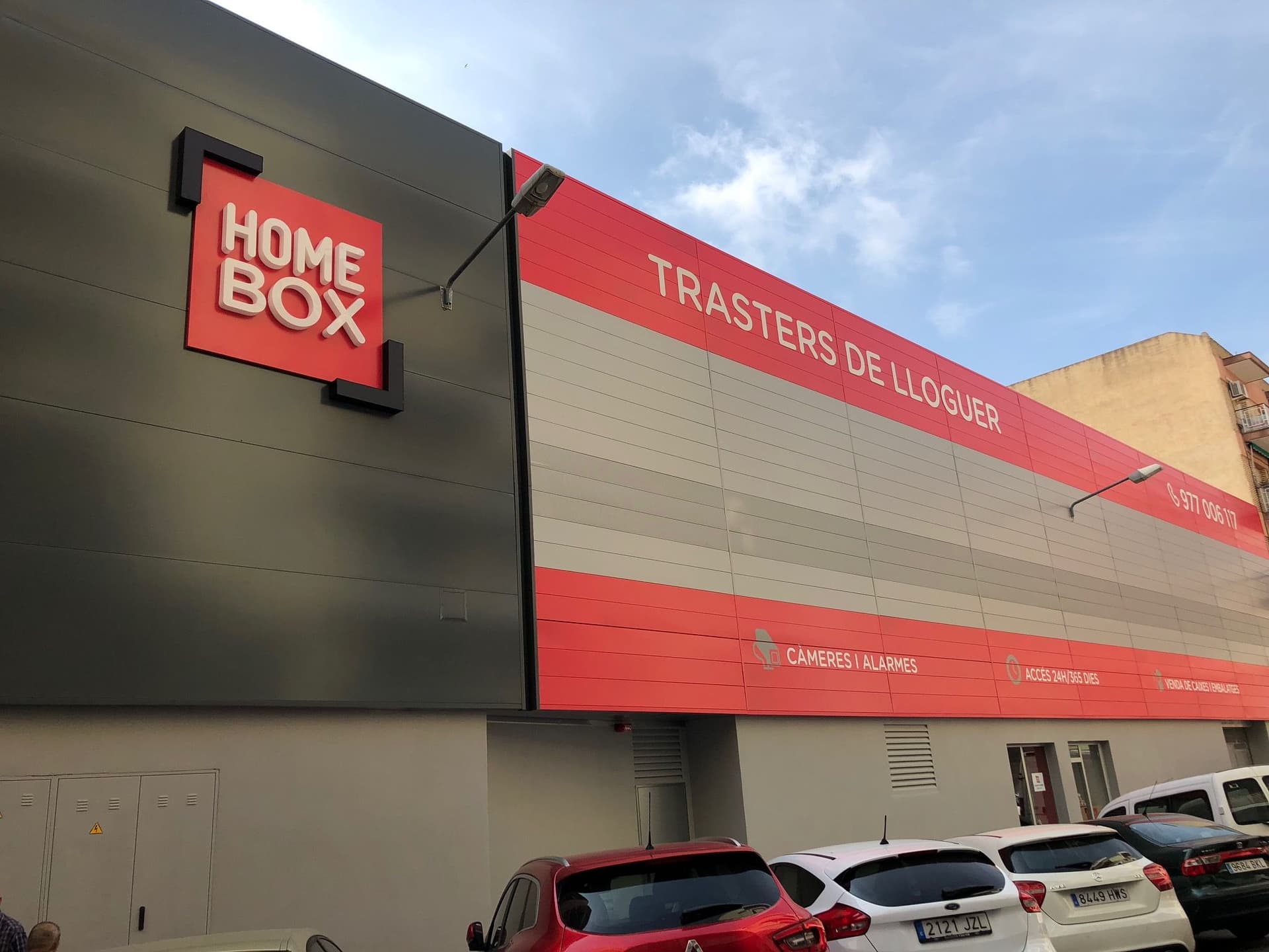 Modern grey facade with large red HOMEBOX sign and rental banner at HOMEBOX Reus, Carrer Benidorm, 4, Reus